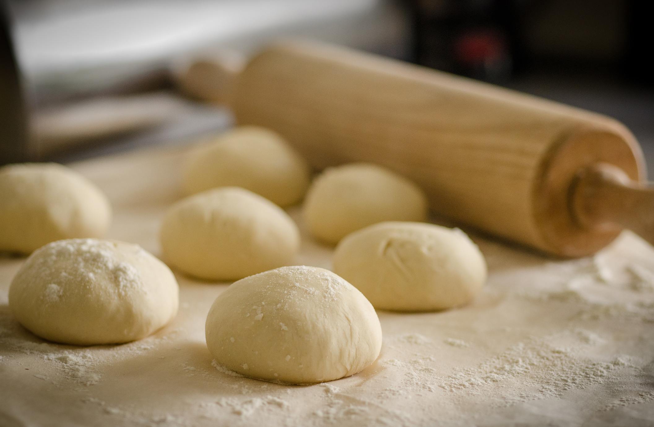 batches of dough on a table next to a rolling pin